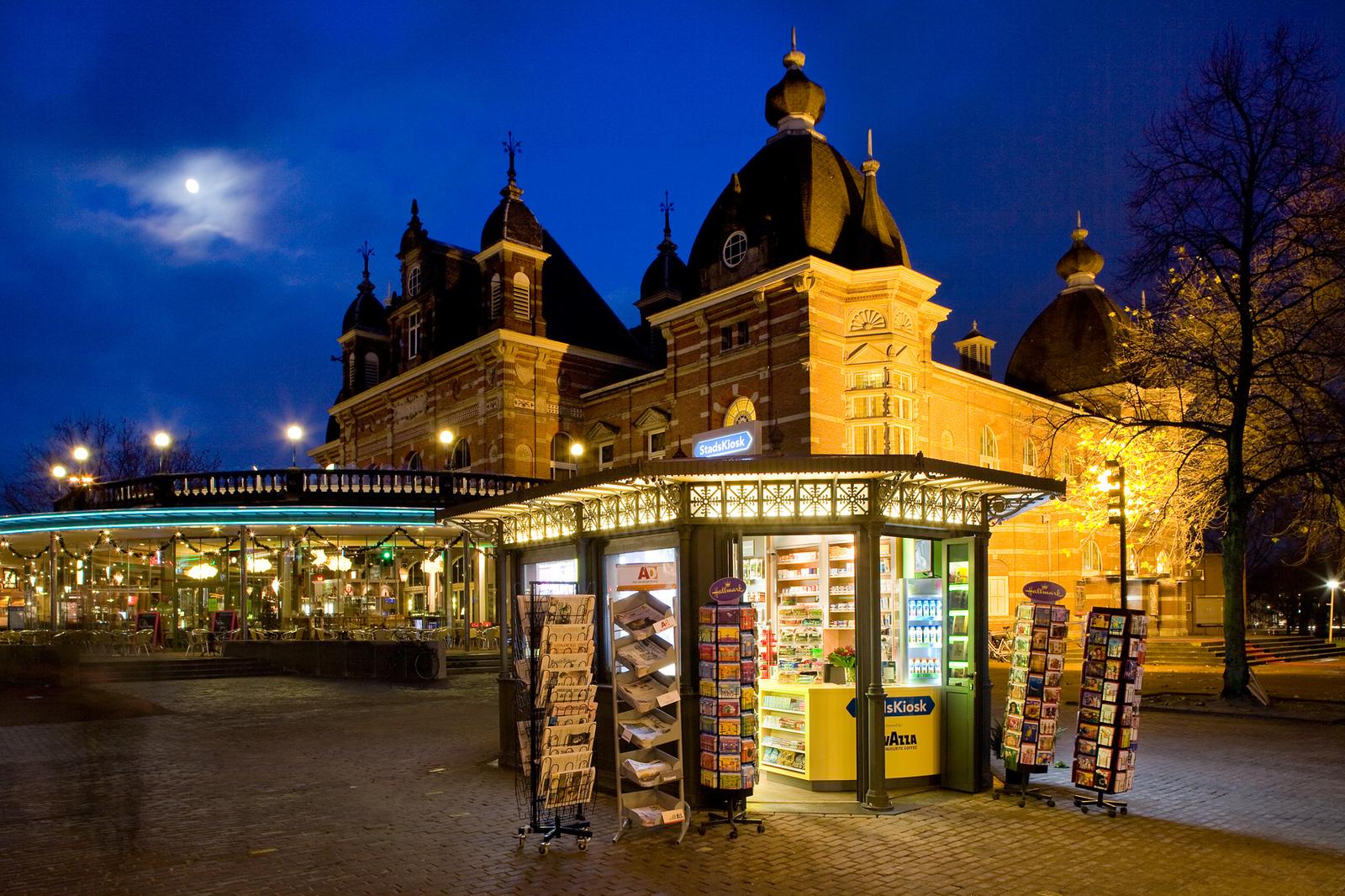 Kiosk bij avond voor het monumentale gebouw